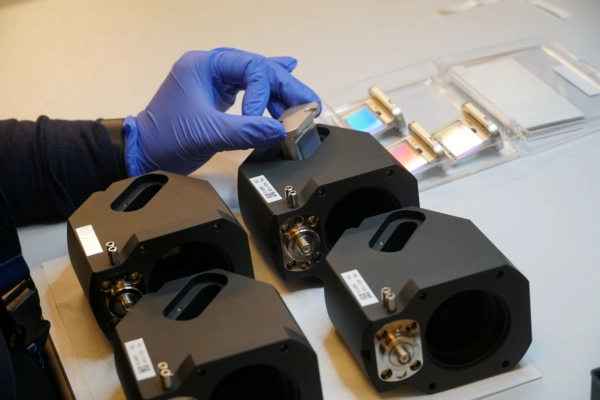 Compact spectrometer modules on workbench Hand with blue glove inserting component in black compact spectrometer modules on a workbench